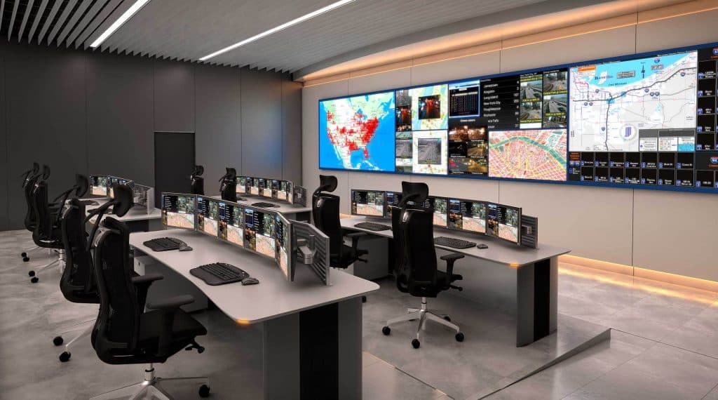 Command-and-control room with a multi-display video wall showing maps and live data feeds
